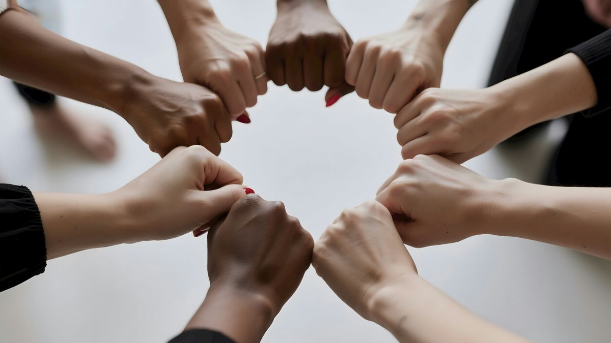 People of diverse skin tones fist bumping in a circle.