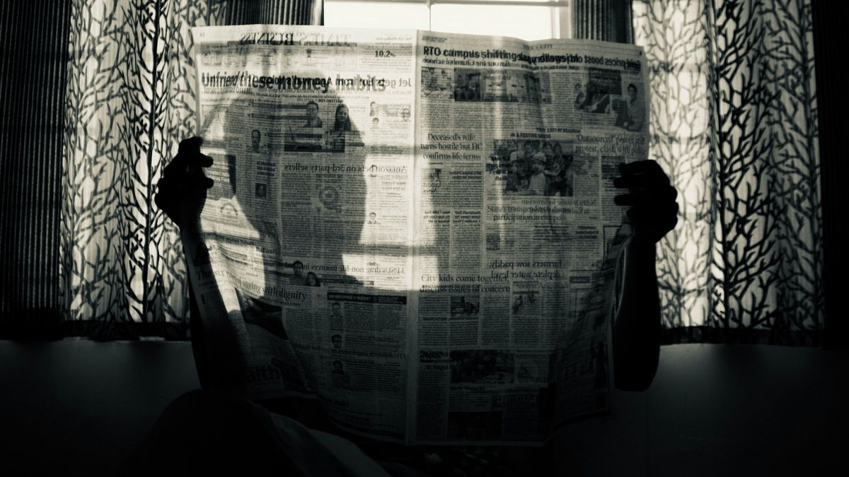 A man holding up a newspaper.